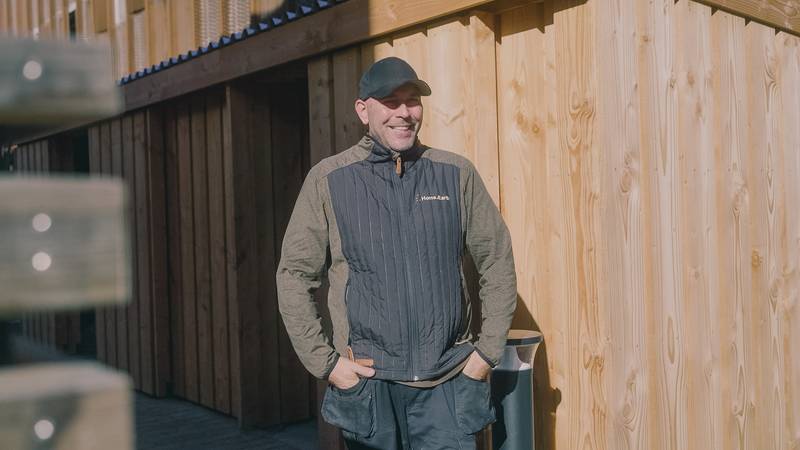 En kollega i Home.Earth-vest står ved nyopsat træbeklædning på en byggeplads.