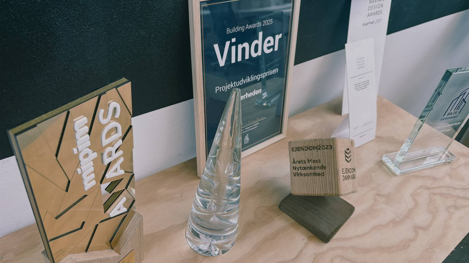 En hylde med branchepriser og diplomer, blandt andet Building Awards og MIPIM.